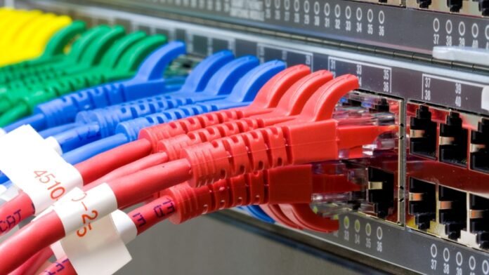 A variety of network switches stacked on a rack in a data center.