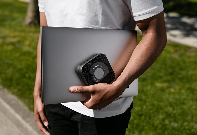 A traveler using a portable Wi-Fi router while working from a café.